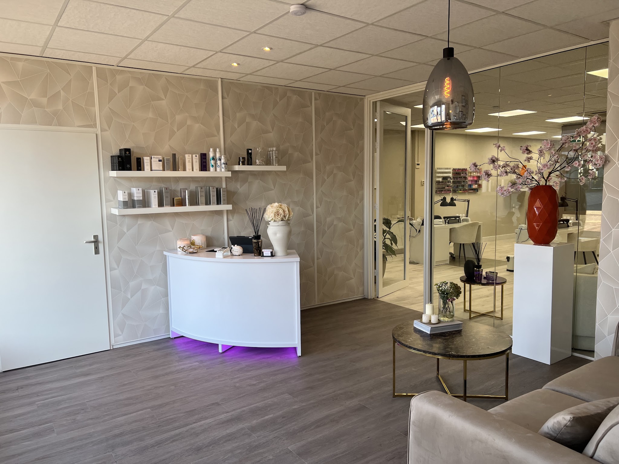 Receptie van Sounds of Beauty met productplanken, witte balie, zitbank en glazen wand