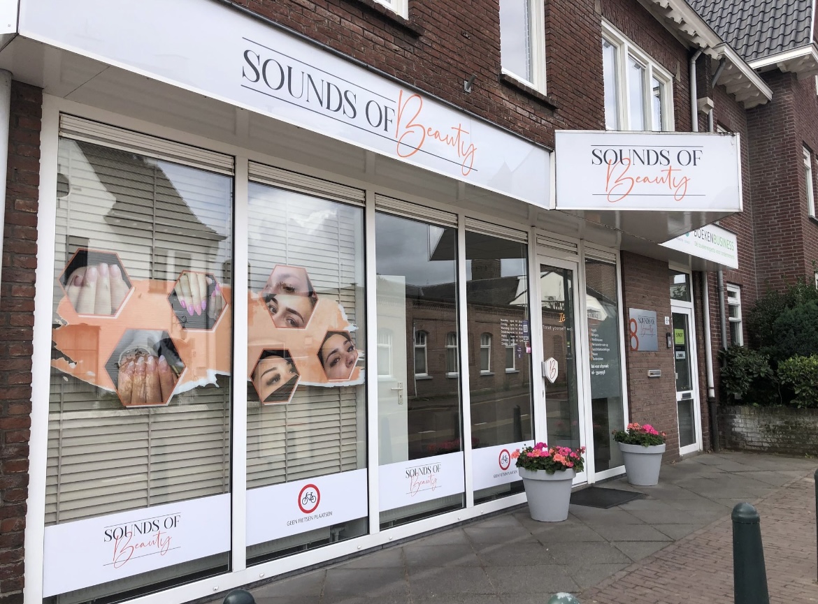 Gevel van Sounds of Beauty aan de Willibrorduslaan, met het logo op de luifel en bloempotten bij de deur