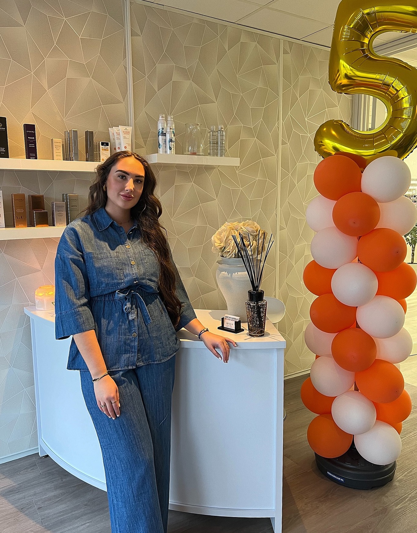 Leandra Janssen bij de receptie van Sounds of Beauty, naast een ballonpilaar met een gouden 5